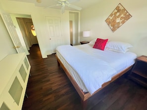 Een hotelkamer met een groot bed, een nachtkastje, een lamp en een plafondventilator.