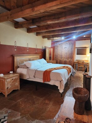 A bedroom with a wooden bed, a nightstand, a dresser, and a stone floor. - Gorgeous Adobe with Kivas & separate Casita, walk river path to Plaza, Patio (Santa Fe)