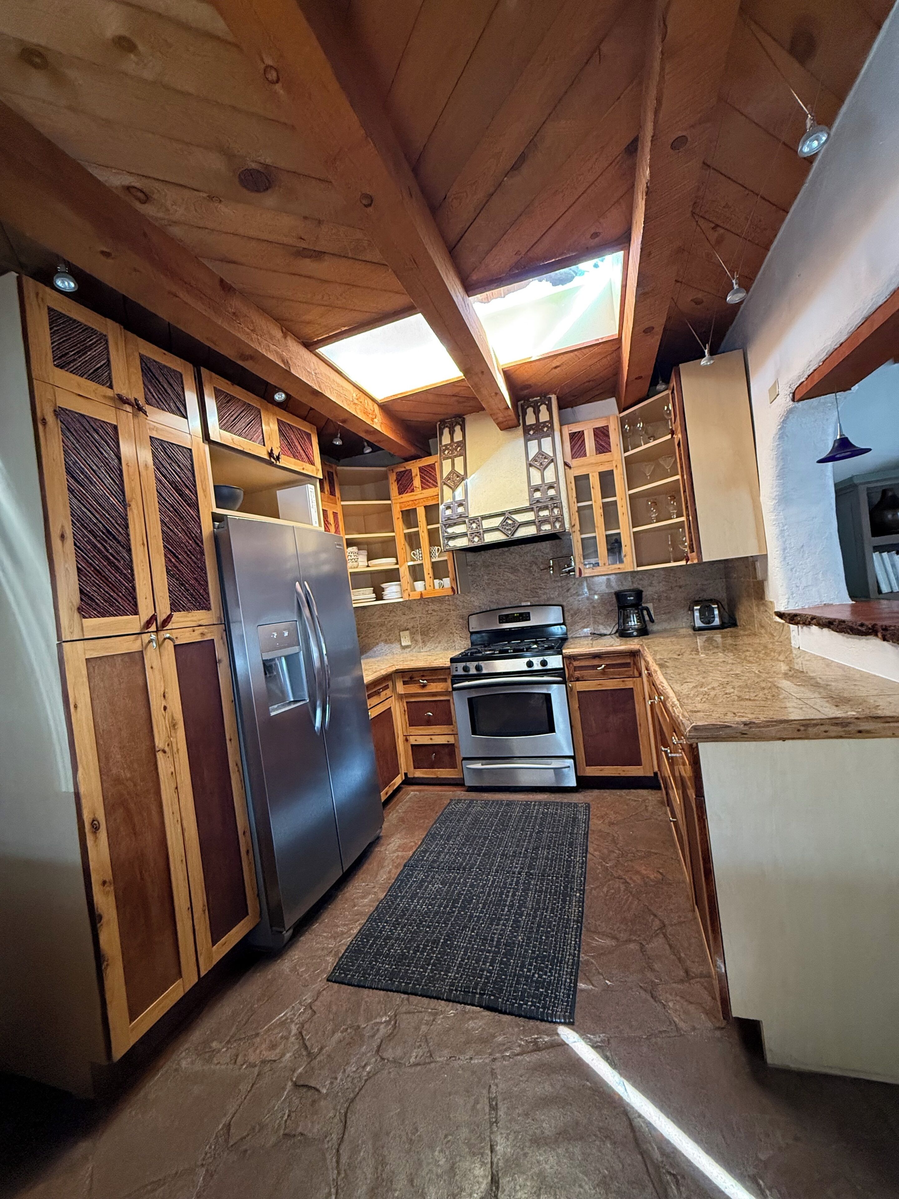 A kitchen with wooden cabinets, a stainless steel refrigerator, a stove, and a microwave.