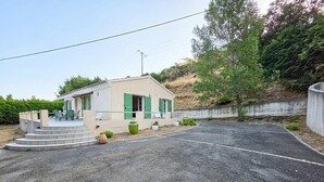 A small house with a paved driveway and steps leading to a porch.