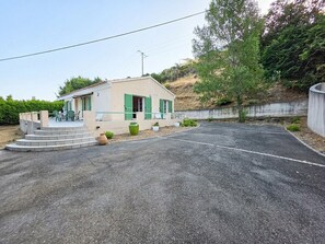 Une petite maison avec une allée pavée et des marches menant à un porche.