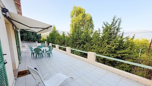 A balcony with outdoor furniture, a table, and chairs.