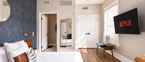 Un dormitorio moderno con una cama, un televisor montado en la pared y un espejo grande.