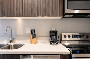 Una cocina con un lavamanos de acero inoxidable, una cafetera, una estufa y armarios de madera.