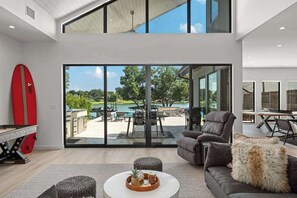 A modern living room with a large sliding glass door leading to an outdoor patio area. - Kingsland Cove - Sleeps 20, Pool & Lake LBJ Dock (Kingsland)