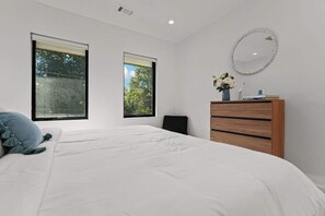 A bedroom with a large bed, two windows, a dresser, and a mirror. - Kingsland Cove - Sleeps 20, Pool & Lake LBJ Dock (Kingsland)