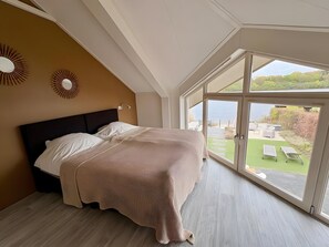 Un dormitorio con una cama, un ventanal y vistas a un jardín.
