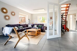 A modern living room with a sectional sofa, a wooden coffee table, and a large window. - Holiday Home 'Beachvilla with Sauna' with Lake View, Wi-Fi and Air Conditioning (Westerhaar-Vriezenveensewijk)