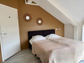 Une chambre à coucher avec un lit, une porte et deux appliques murales.