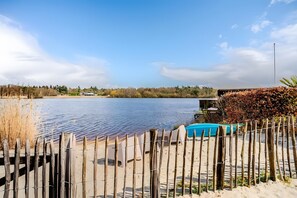 Vista de un lago con una valla de madera, una piscina azul y un edificio al fondo.