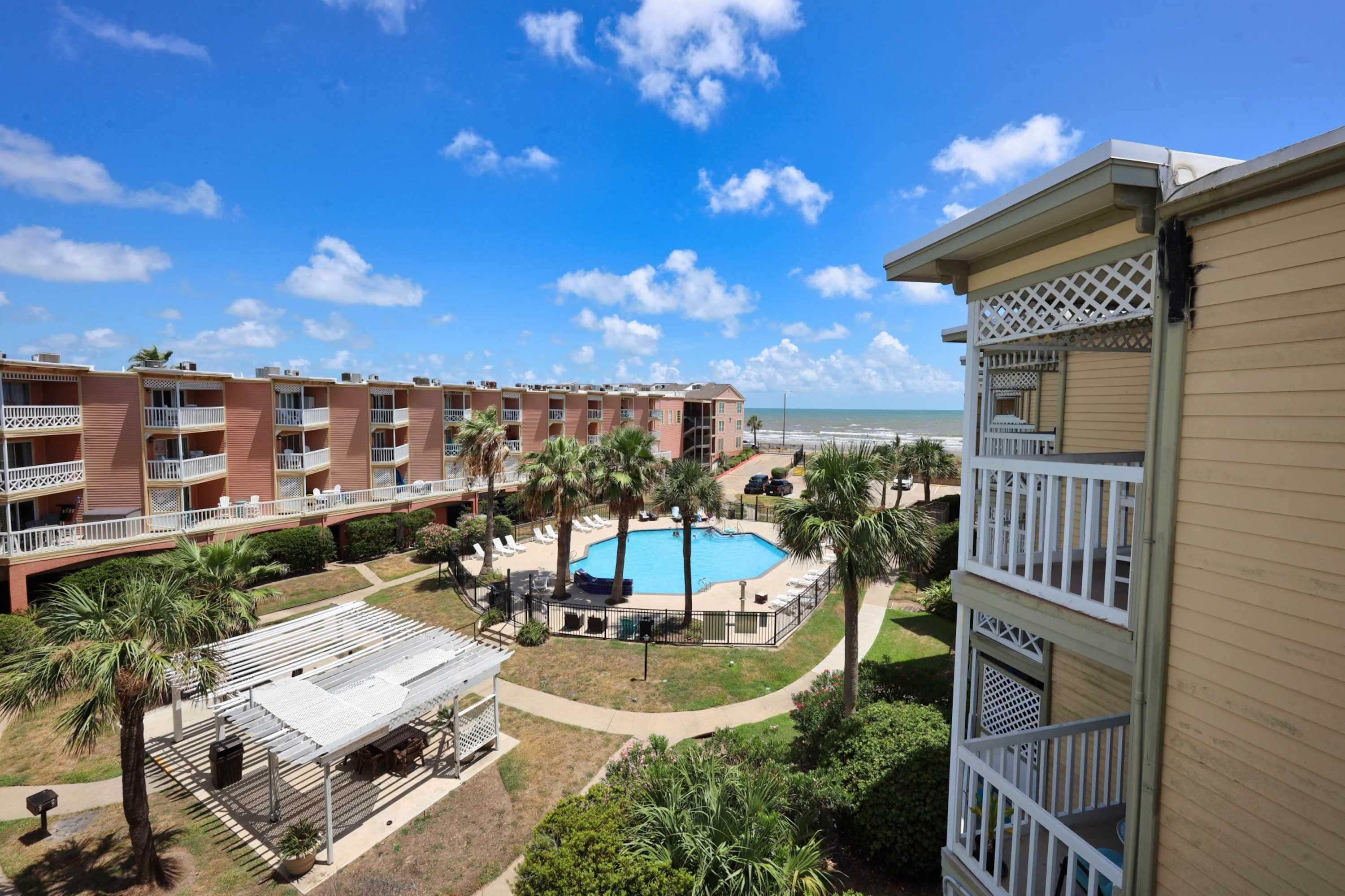 A hotel with multiple balconies, a swimming pool, and a view of the beach.