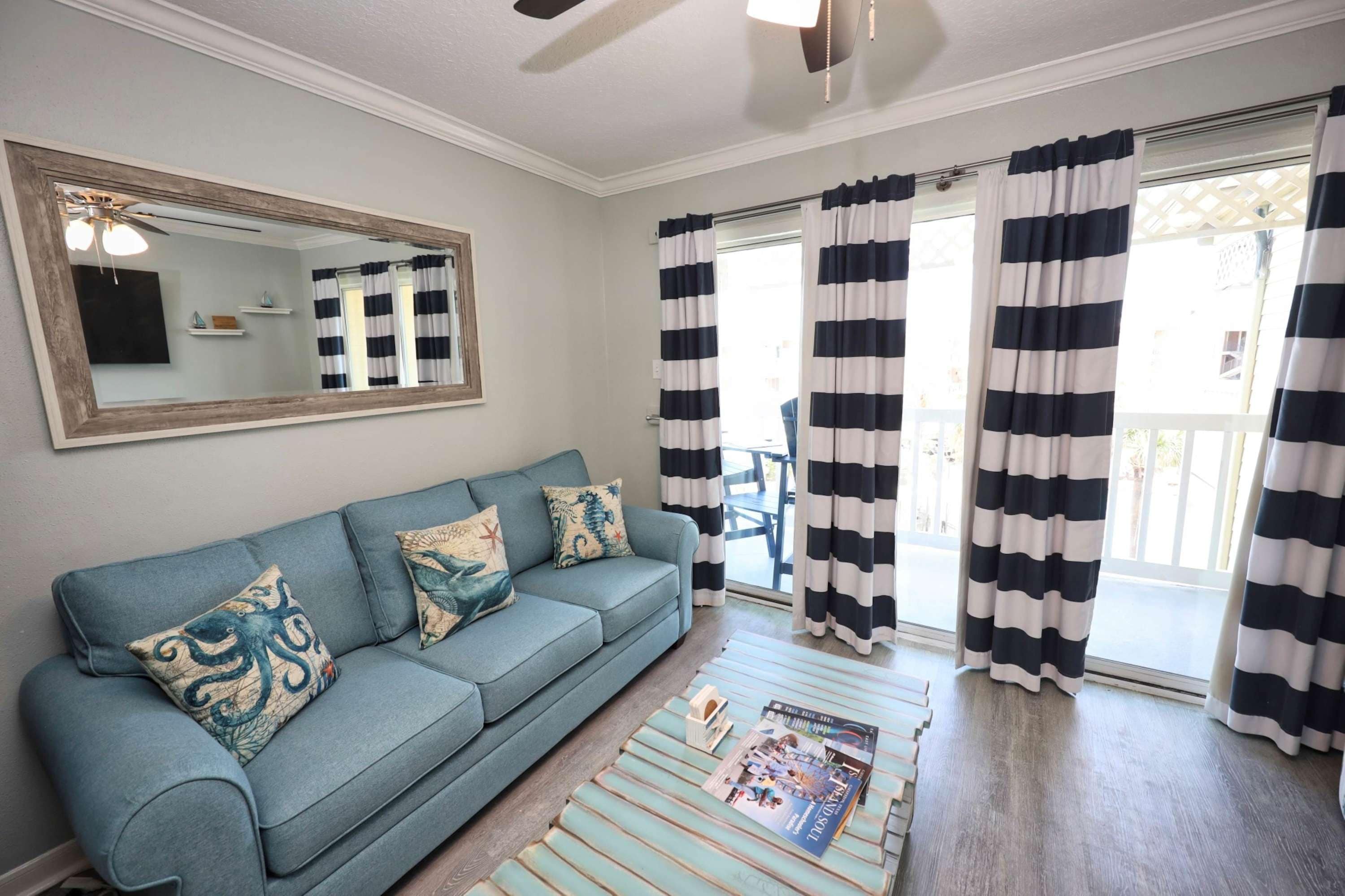 A living room with a sofa, pillows, a coffee table, and a magazine.