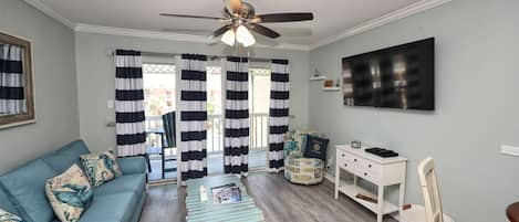 A living room with a sofa, a coffee table, a desk, and a ceiling fan.