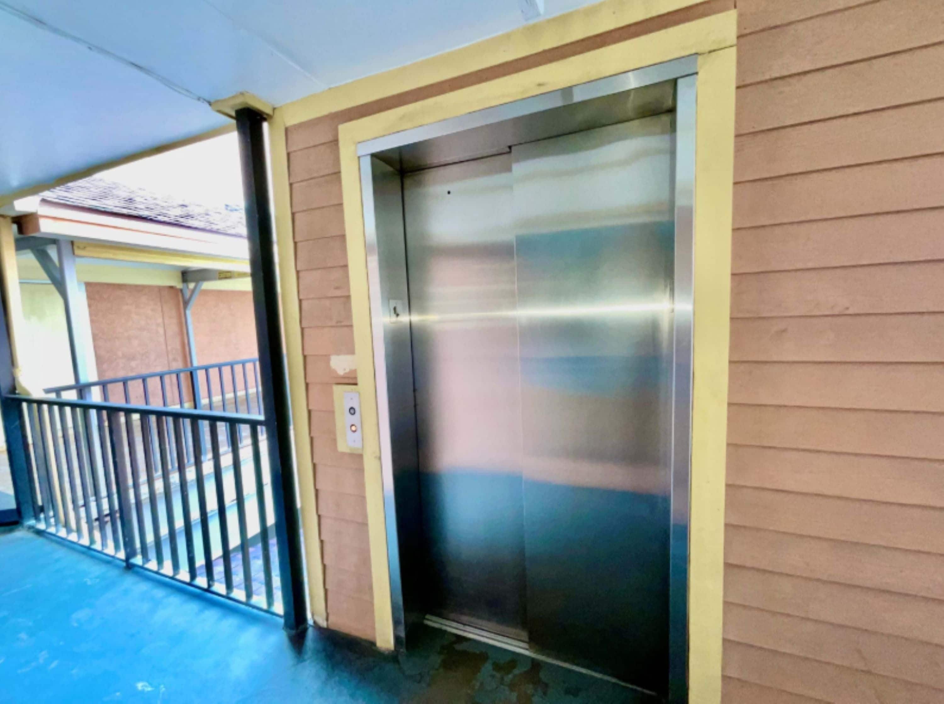 An elevator with a metallic finish, a control panel, and a door.