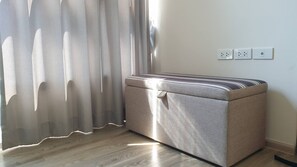 Ein Zimmer mit einem großen, gemusterten Schrank an der Wand, einem Fenster mit transparenten Vorhängen und einer Steckdose mit drei Steckbuchsen.