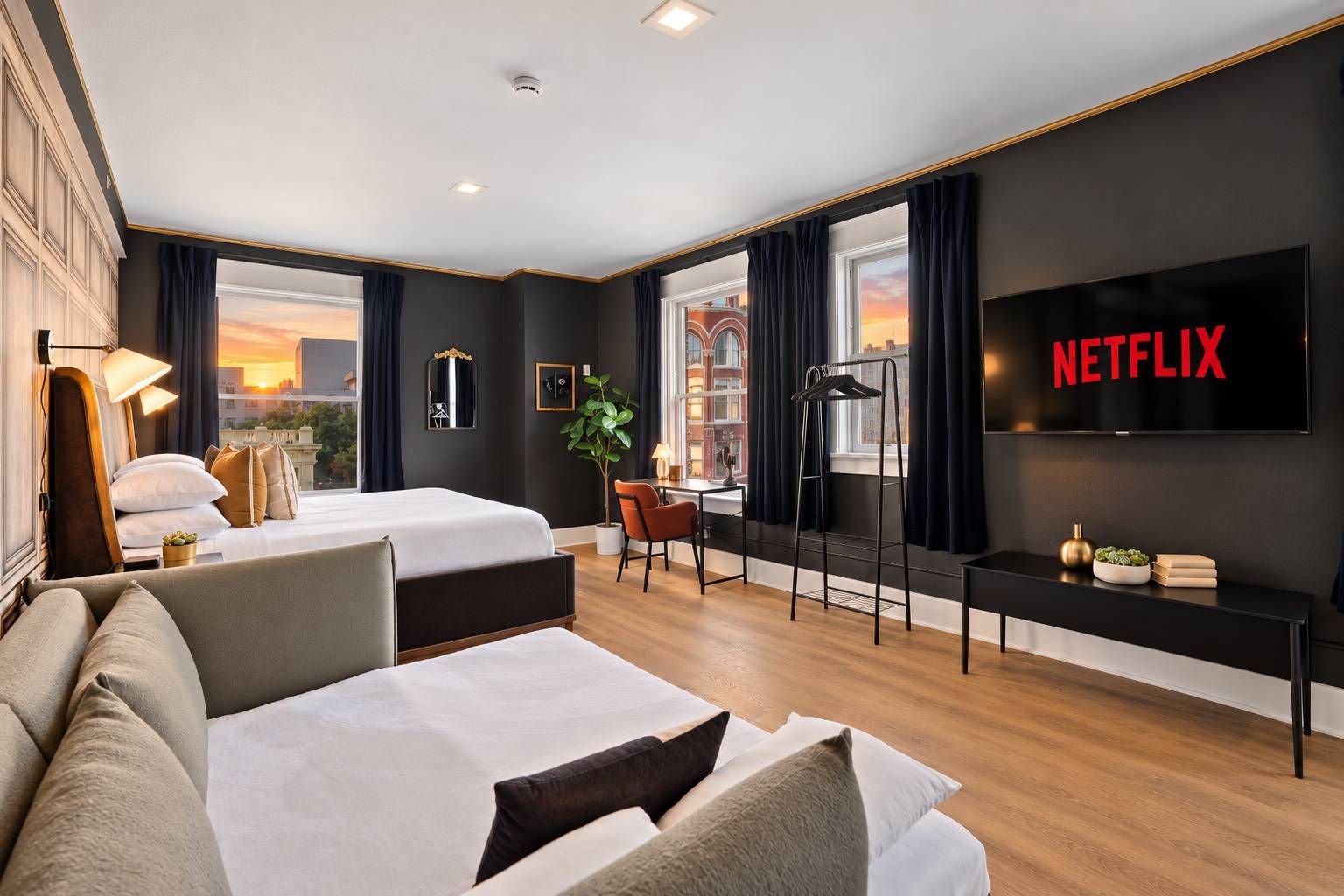 Habitación de hotel con cama, sofá, escritorio, televisor y vistas a la ciudad.