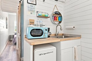A compact kitchenette with a light blue microwave, a sink, and a small fridge. - Container Retreat: Unit 11 (Fredericksburg)