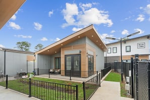 Una casa moderna con balcón, patio cercado y cielo despejado.