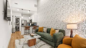 Una sala moderna con un sofá verde, una mesa de centro y una pared con diseño.