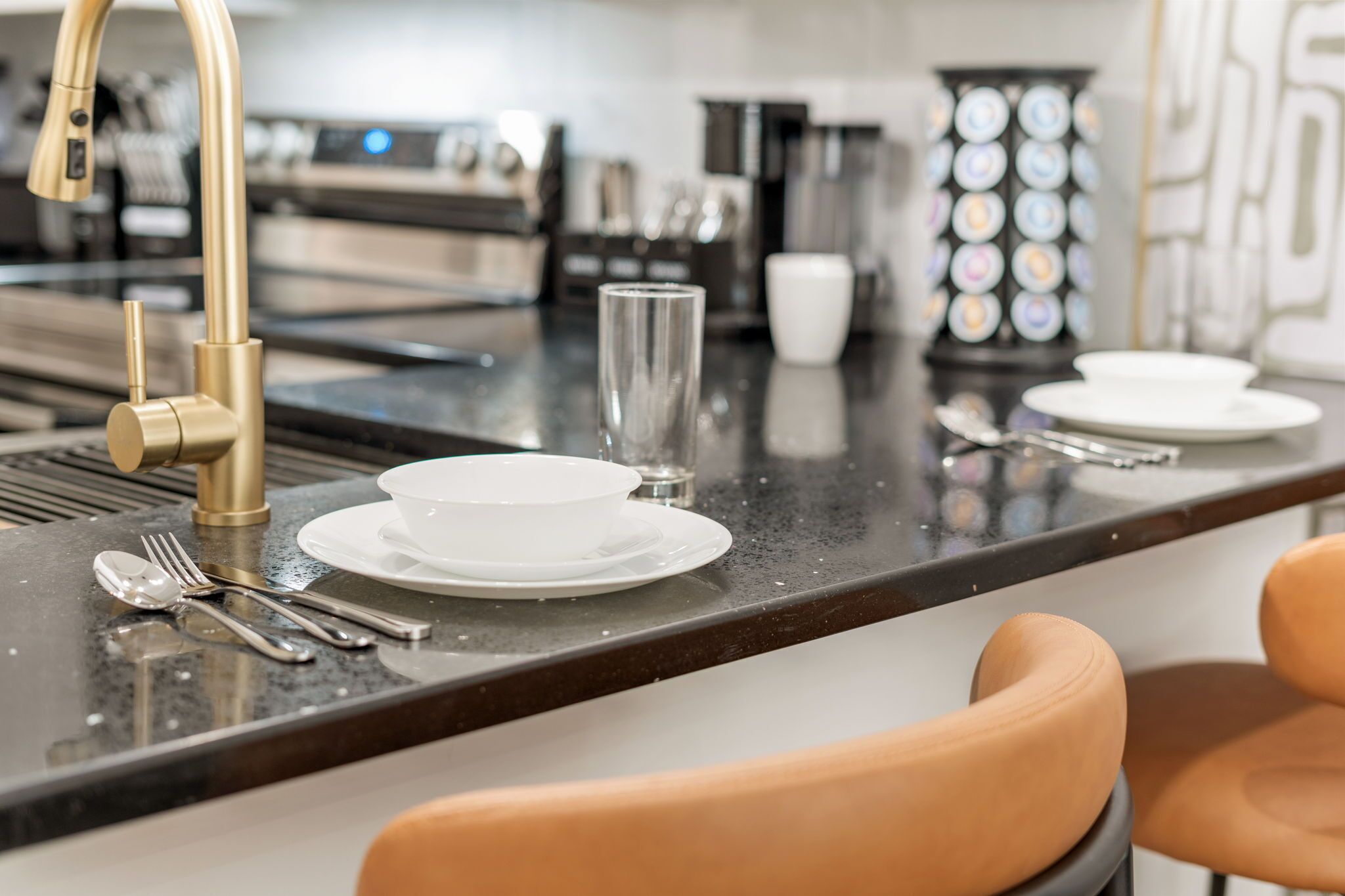 A modern kitchen with a central island, stainless steel appliances, and a gold faucet.