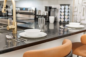 Une cuisine moderne dotée d’un îlot central, d’appareils électroménagers en acier inoxydable et d’un robinet doré.