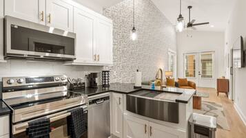 A modern kitchen with stainless steel appliances, white cabinetry, and a patterned backsplash.