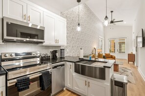 Une cuisine moderne dotée d’appareils électroménagers en acier inoxydable, de meubles blancs et d’un revêtement mural décoratif.