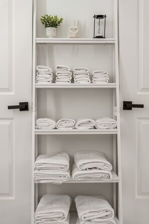 Un porte-serviettes blanc doté de plusieurs étagères où sont pliés les serviettes.