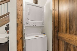 A compact, white front-loading washer and dryer unit with control knobs and a small storage compartment. - Creekside Cabin - Cozy Stay (Hollister)