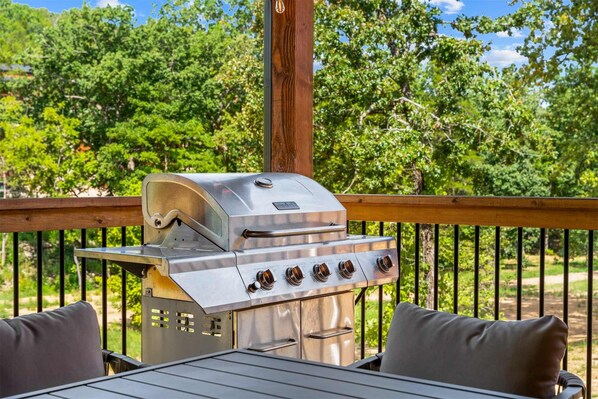 Un barbecue extérieur avec une terrasse en bois et une table entourée de chaises.