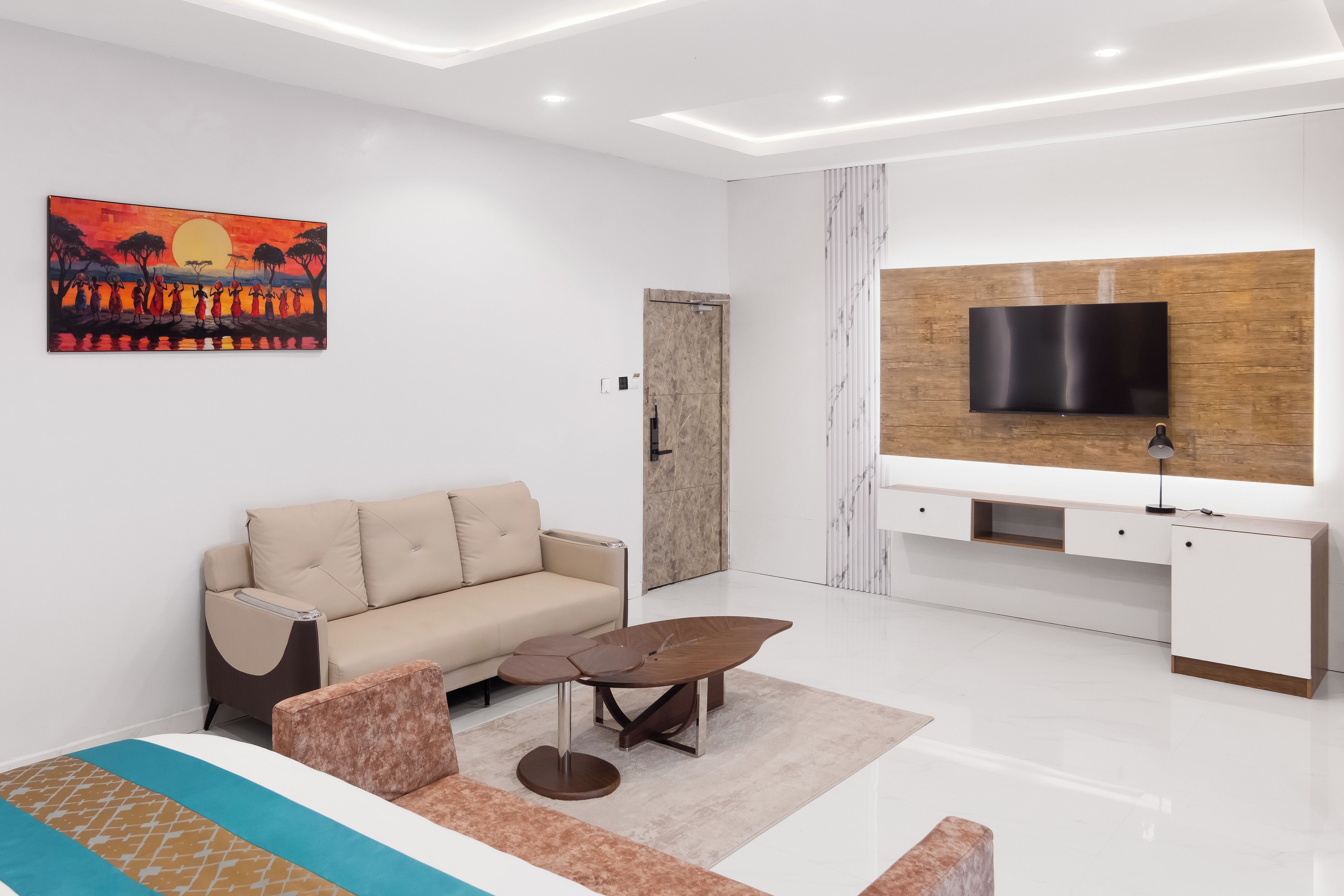 A modern living room with a sofa, coffee table, TV, and artwork.