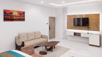 A modern living room with a sofa, coffee table, TV, and artwork.