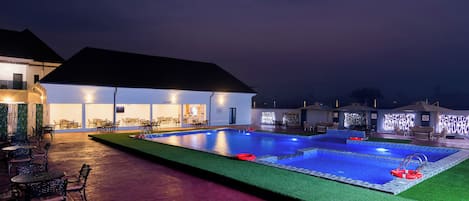 A swimming pool with a bar area, outdoor seating, and a covered patio.
