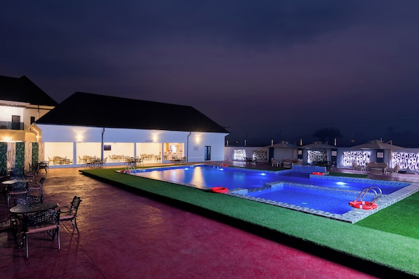 A swimming pool with a bar area, outdoor seating, and a covered patio.
