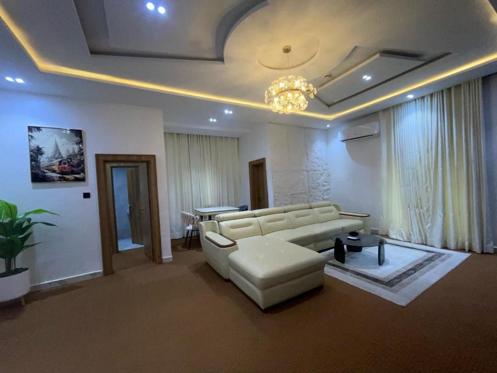 A modern living room with a sectional sofa, a dining table, and a chandelier.
