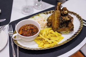 A plate with fried chicken, French fries, coleslaw, and a bowl of stew.