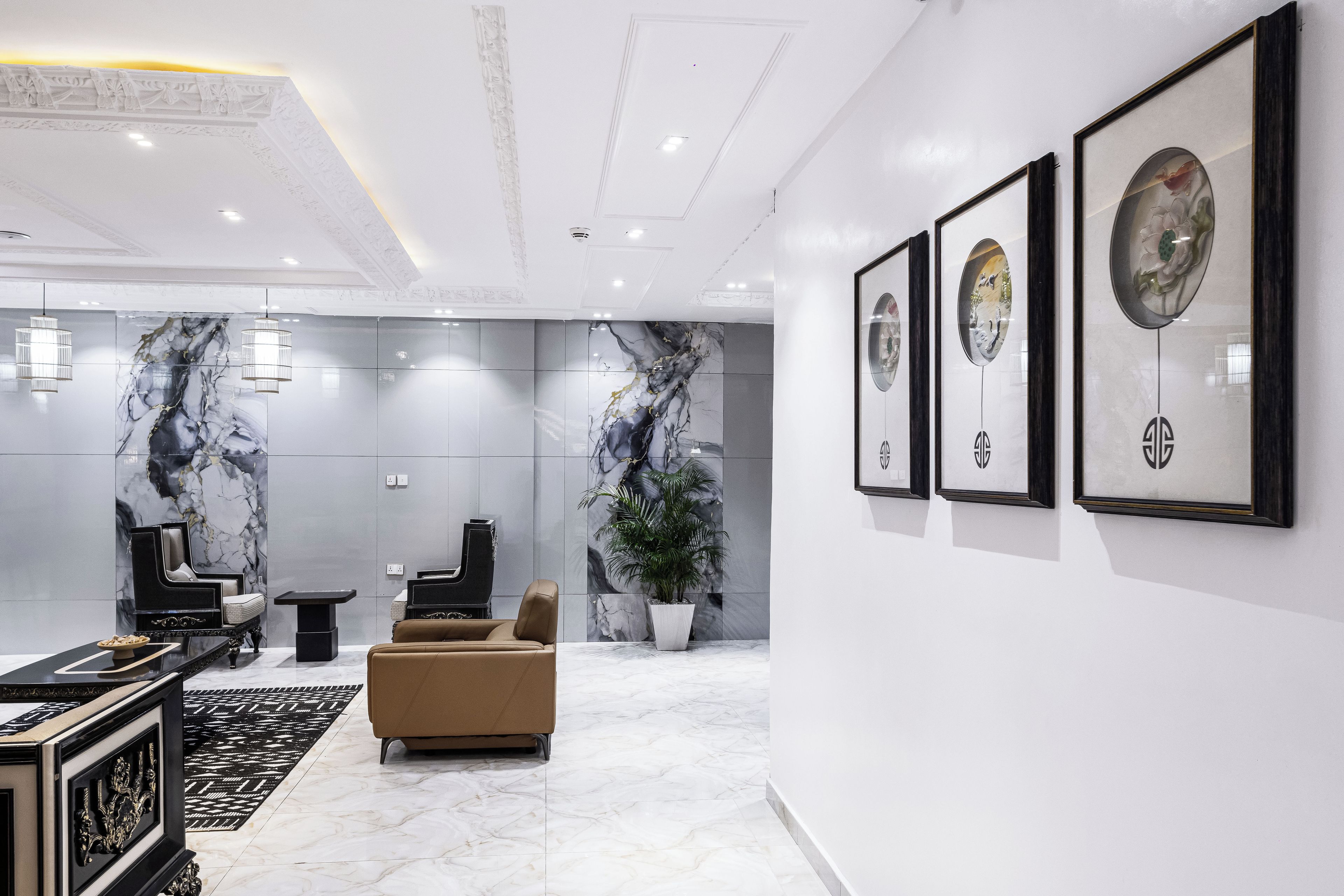 A modern lobby with marble walls, a black piano, a beige sofa, and framed artwork on the wall.