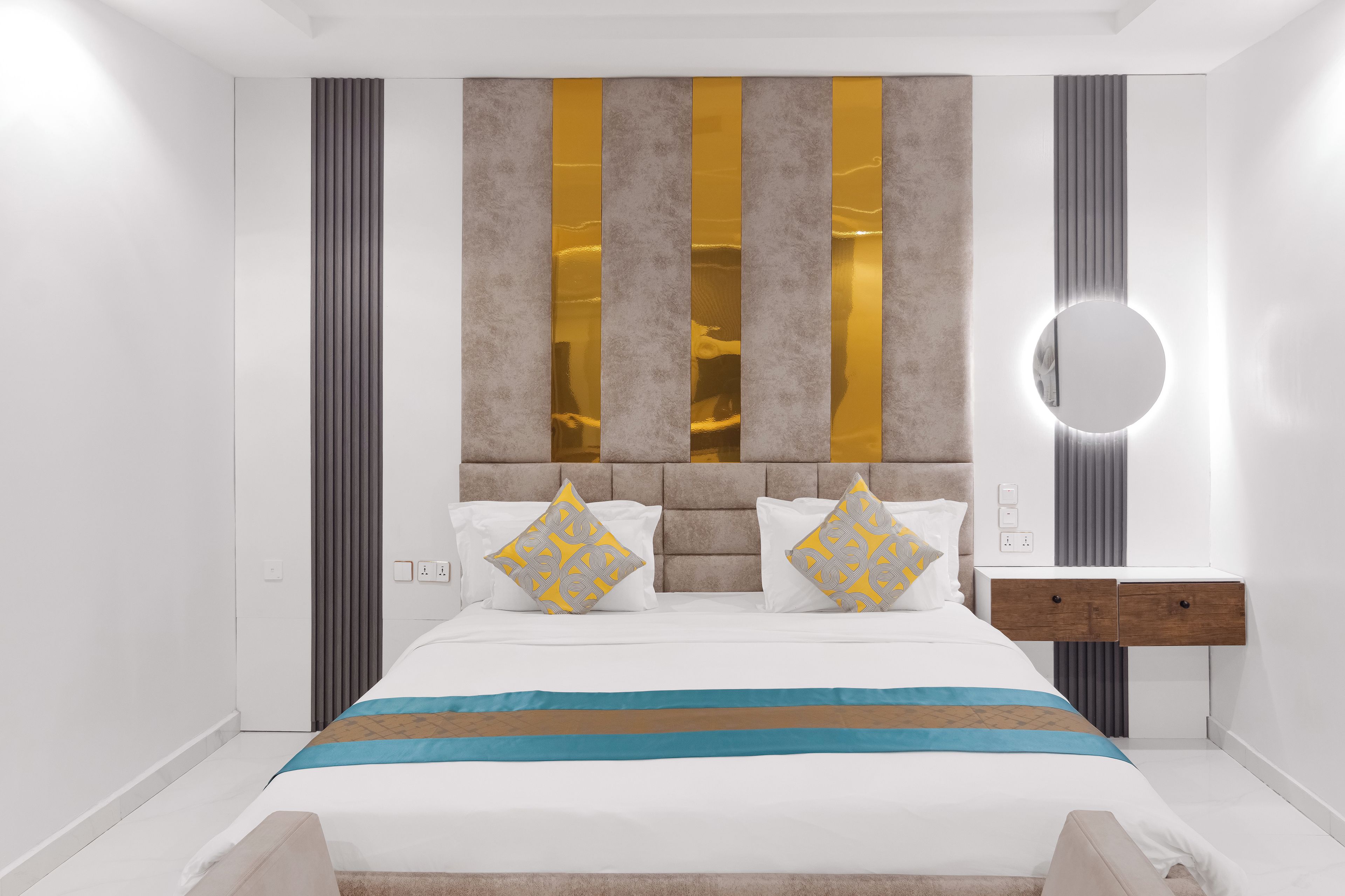 Ein modernes Schlafzimmer mit einem großen Bett, einem Nachttisch und einem runden Wandspiegel.