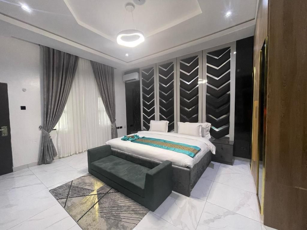 Un dormitorio moderno con una cama grande, un banco y un panel decorativo en la pared.