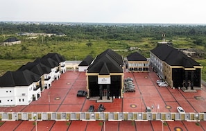 A hotel with a red parking lot and multiple buildings with black roofs.