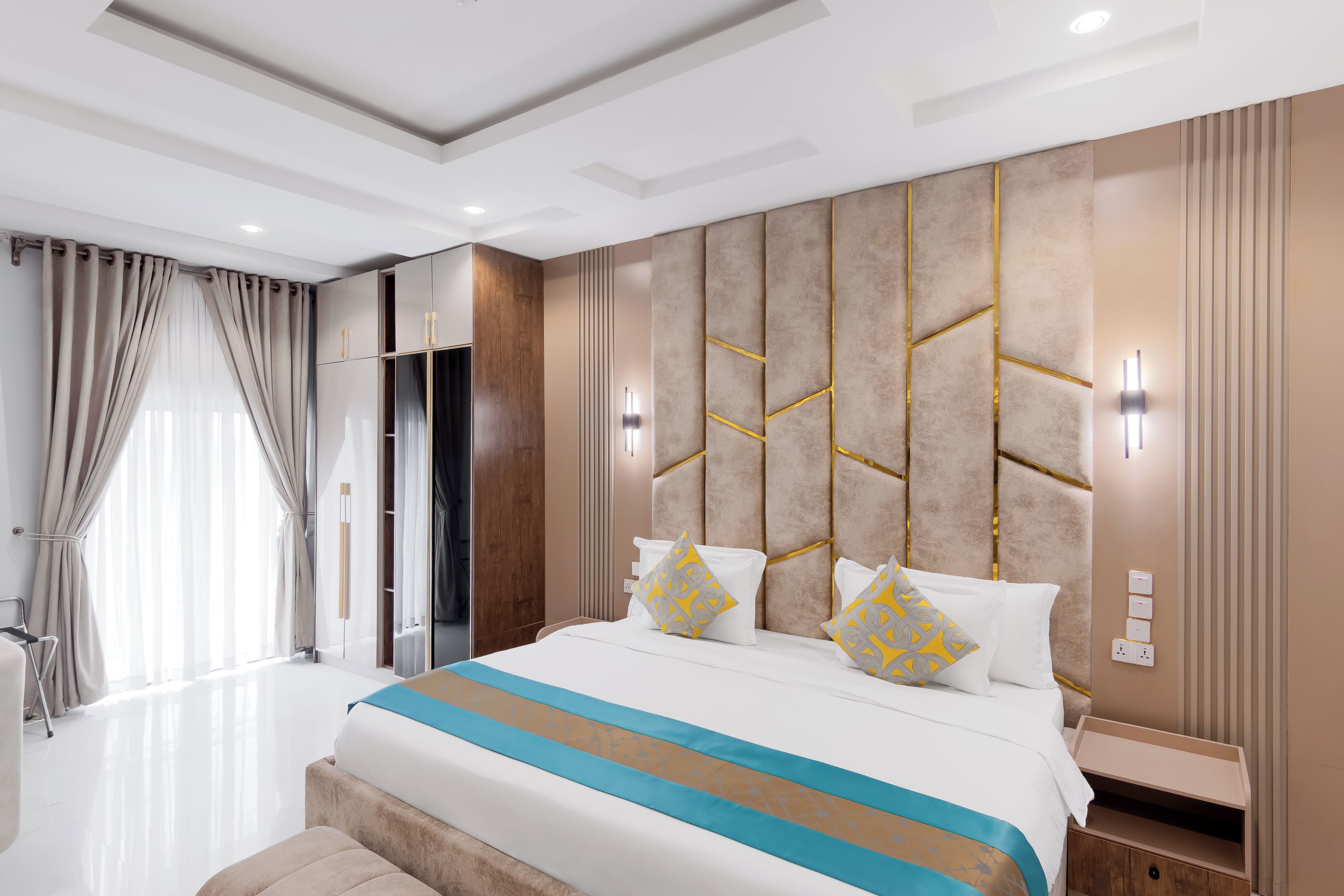 A modern hotel room with a large bed, bedside tables, a wardrobe, and a bathroom with a shower.