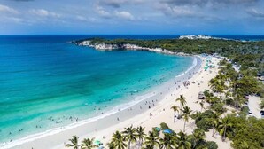 Una playa con aguas turquesas cristalinas, una orilla de arena y palmeras.