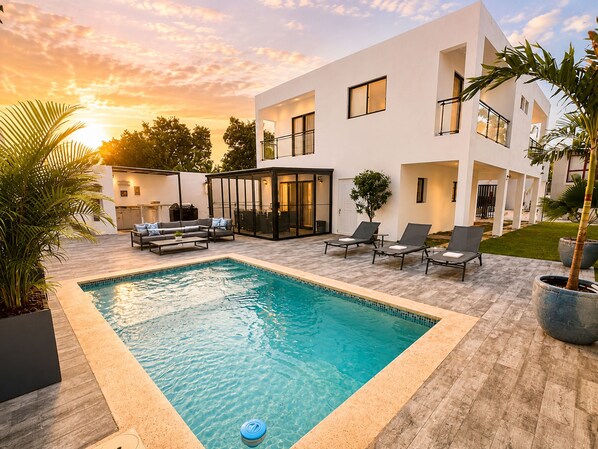 A modern outdoor pool area with a rectangular pool, lounge chairs, and a covered seating area. - Private Pool Villa 3BR | Gated, 10 Min Downtown (Punta Cana)