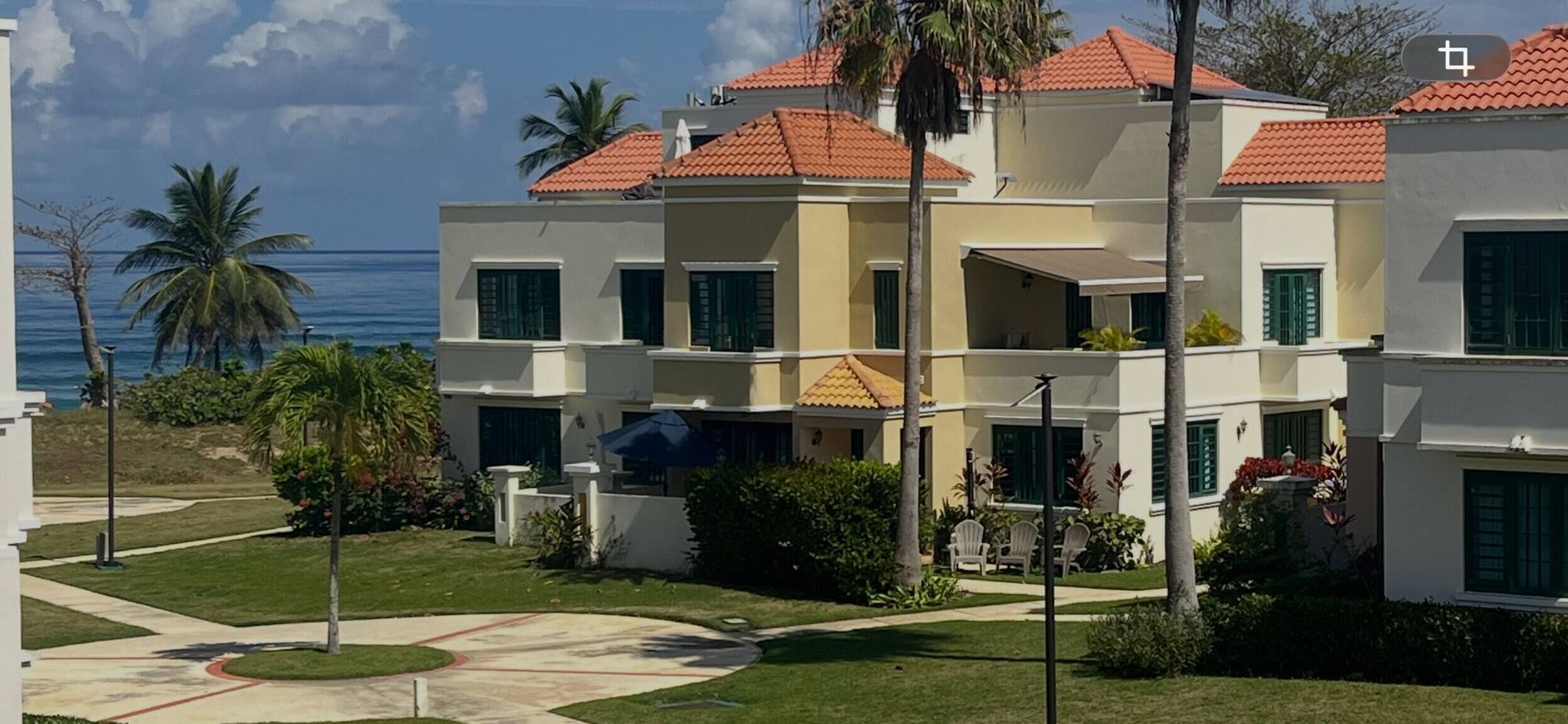 A multi-story hotel with balconies, a pool area, and a view of the ocean.