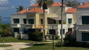 Et hotel med flere etager, altaner, et poolområde og udsigt over havet.