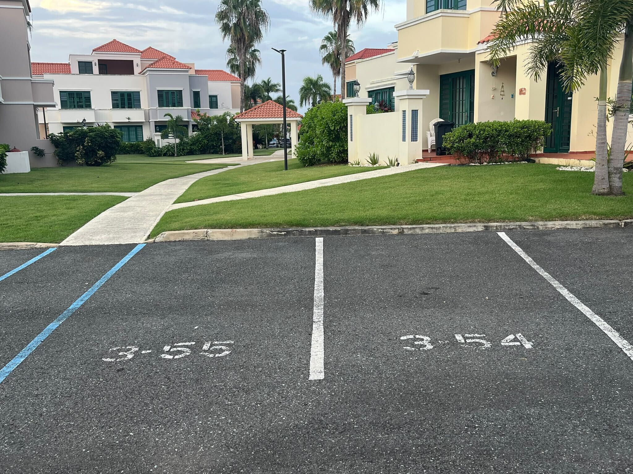 Un parcheggio con posti auto delimitati e un percorso che porta a un edificio con tetto in tegole rosse.