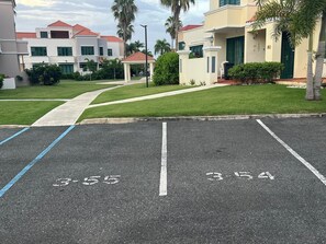 A parking lot with marked spaces and a pathway leading to a building with a red-tiled roof.