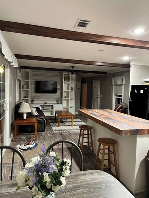 A modern kitchen with a bar area, wooden beams, and a dining space with a table and chairs. - Quiet country setting, river retreat dunnellon (Dunnellon)