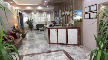 Un hall de hotel con mostrador de recepción, zona de estar y vista a la montaña.