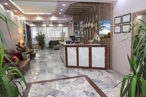 A hotel lobby with a reception desk, seating area, and a view of a mountain. - Alkış Otel (Igdir)